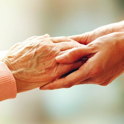 The hand of a younger person holds the hand of an older person